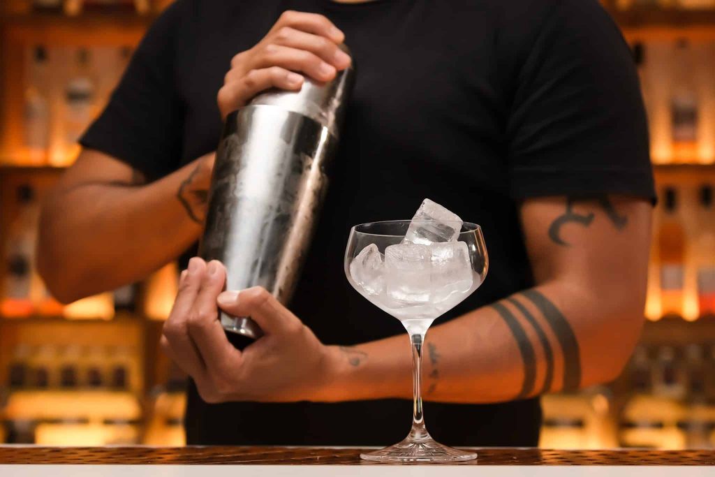 A bartender holding a chilled martini shaker.